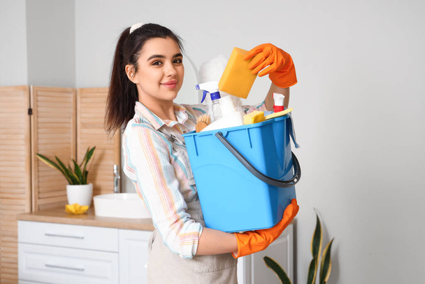 Young woman with cleaning supplies in bathroom - Photo, Image