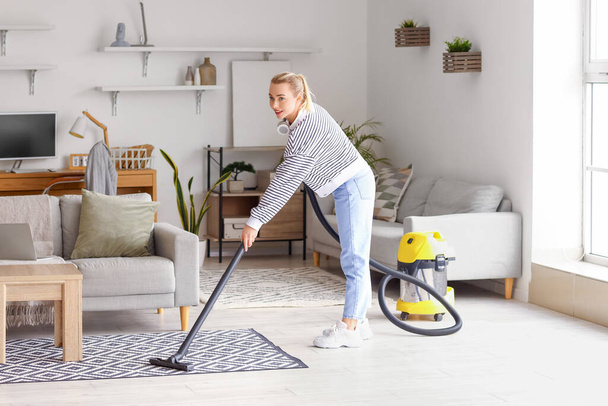 Молода жінка прасує килим вдома
 - Фото, зображення