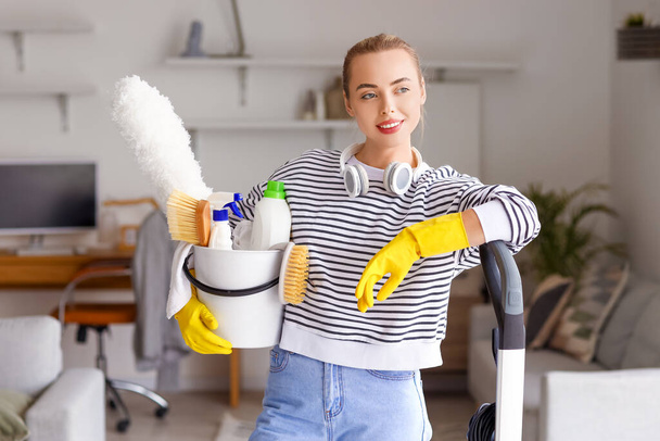 Jeune femme avec seau de fournitures de nettoyage à la maison - Photo, image