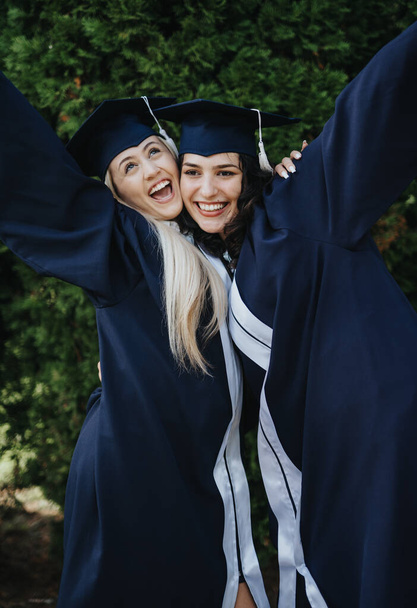 多様な女性大学卒業生が屋外で祝っています. 笑顔,抱擁,そして成功を達成する幸せな思い出を共有する. - 写真・画像
