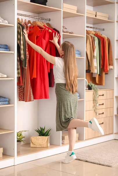 Nuori nainen valitsemalla vaatteita boutique
 - Valokuva, kuva