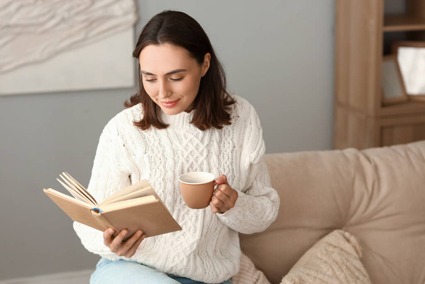 Junge Frau mit Tasse Kaffee liest Buch zu Hause - Foto, Bild