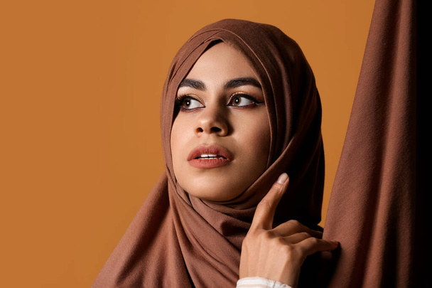 Bella giovane donna afro-americana musulmana con un bel trucco su sfondo marrone - Foto, immagini