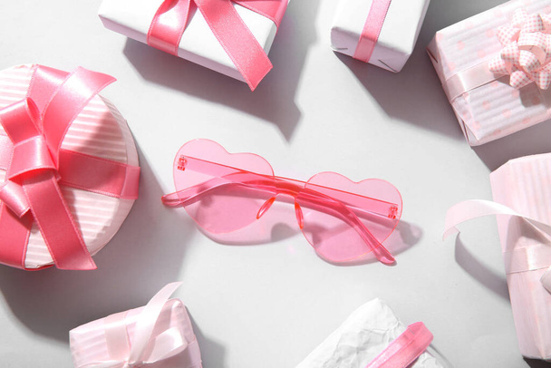 Рожеві окуляри у формі серця з подарунками на білому тлі. Концепція Дня Святого Валентина - Фото, зображення