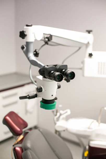 Стоматологічний мікроскоп на тлі сучасної стоматології. Медичне обладнання. Стоматологічний операційний мікроскоп з поворотним подвійним біноклем
. - Фото, зображення