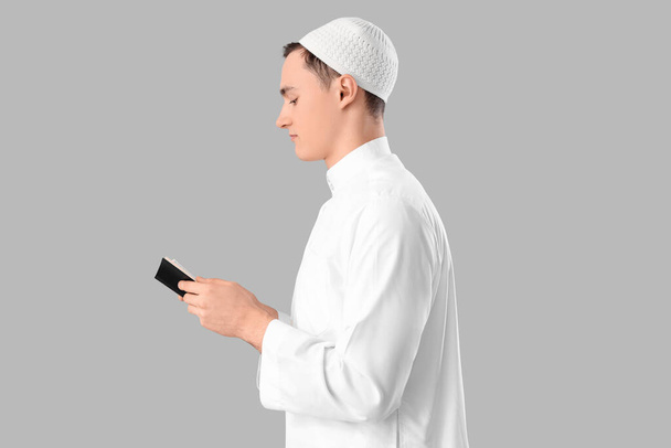 Jeune homme musulman avec Coran sur fond clair. Fête du Ramadan - Photo, image