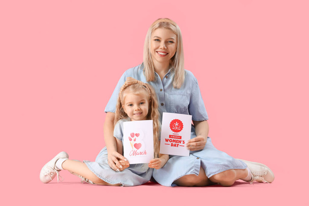 Маленькая девочка и ее мать с поздравительными открытками на розовом фоне. Международный женский день - Фото, изображение