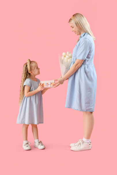 Mała dziewczynka i jej matka z prezentami na różowym tle. Międzynarodowy Dzień Kobiet - Zdjęcie, obraz