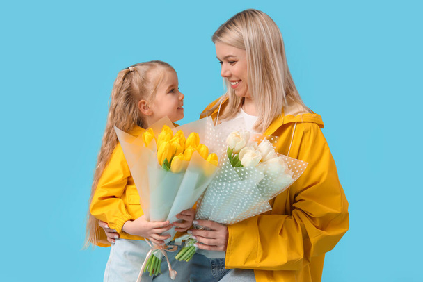 Little girl and her mother with tulips on blue background. International Women's Day celebration - Photo, Image