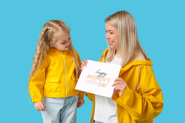 Маленька дівчинка та її мати з вітальною листівкою на синьому фоні. Міжнародний жіночий день - Фото, зображення