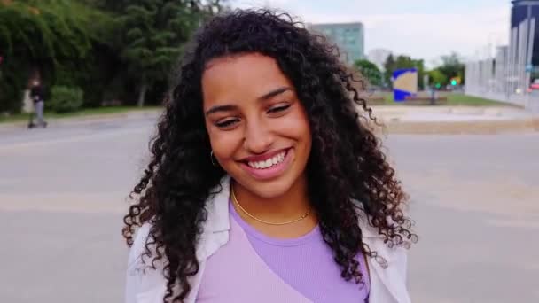 Šťastná mladá latinskoamerická dívka se usmívá na kameru stojící na City Street. Venku portrét radostné krásné ženy na městském pozadí. - Záběry, video