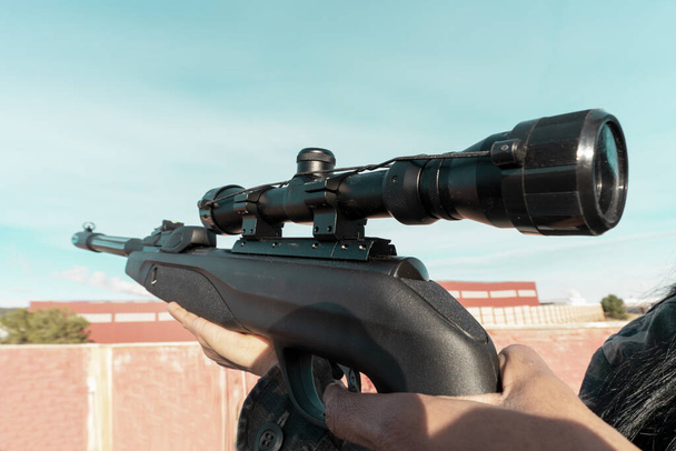 Гвинтівка з оптичним прицілом крупним планом в руках чоловіка, вибірковий фокус. Військові дії, снайперський знімальний процес. - Фото, зображення