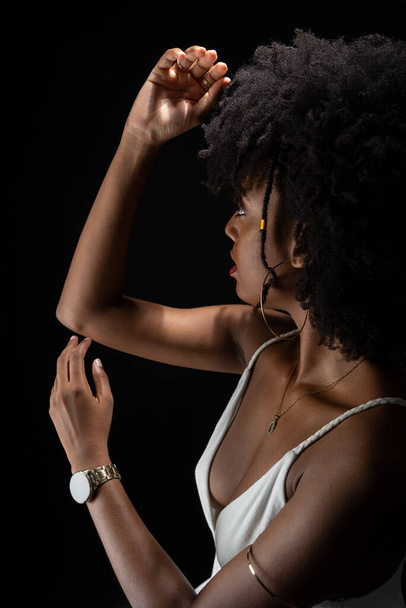 Schöne Frau mit schwarzem Power-Haar, die Bewegungen mit ihren Armen macht. In weißer Kleidung. Vereinzelt auf schwarzem Hintergrund. - Foto, Bild