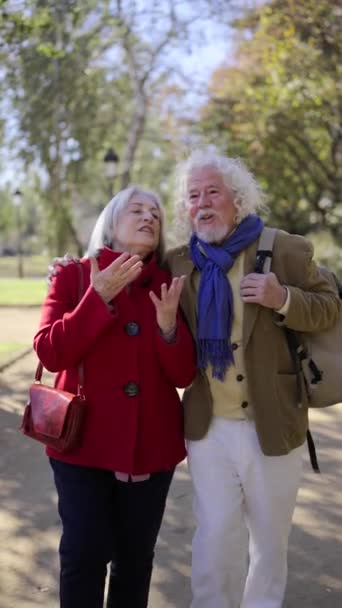 Vidéo d'un heureux couple de personnes âgées se promenant le long d'un parc, se tenant la main et parlant par une journée ensoleillée - Séquence, vidéo