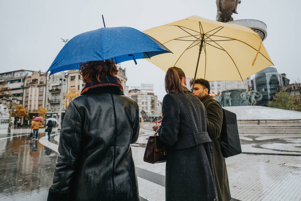 Üzleti partnerek megvitatják a projektet egy esős napon a városban, egy esernyőt használva, hogy száraz maradjon, miközben együtt dolgoznak az üzleti terjeszkedés és a nyereség növelése érdekében. - Fotó, kép