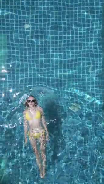 Draufsicht einer jungen Kaukasierin, die in Zeitlupe auf dem Rücken im Pool schwimmt. - Filmmaterial, Video