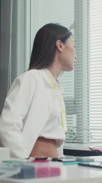 Vertical de mujer especialista en labcoat blanco reparando teléfono móvil en mesa de trabajo en centro de servicio - Metraje, vídeo