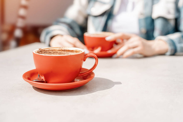 Μια γυναίκα που πίνει καφέ στο καφέ του δρόμου με μια φίλη έξω, διασκεδάζοντας. έννοια τρόπου ζωής - Φωτογραφία, εικόνα