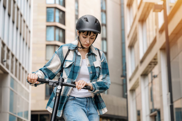 Молода жінка в сорочці і шоломі з електричним скутером у міському місті концепція способу життя людей - Фото, зображення