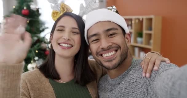 Ευτυχισμένος, ζευγάρι και βιντεοκλήση στο σπίτι τα Χριστούγεννα με τα μέσα κοινωνικής δικτύωσης, συνομιλία και κύμα. Άνθρωποι, selfie και ζωντανή ροή στο σαλόνι με εικονική επαφή, επικοινωνία ή συζήτηση για τις διακοπές. - Πλάνα, βίντεο