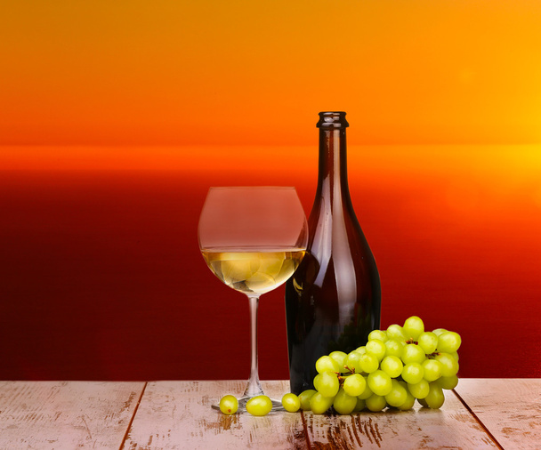 Weißweintrauben in einem Glas bei Sonnenuntergang auf einem Stück Holz - Foto, Bild