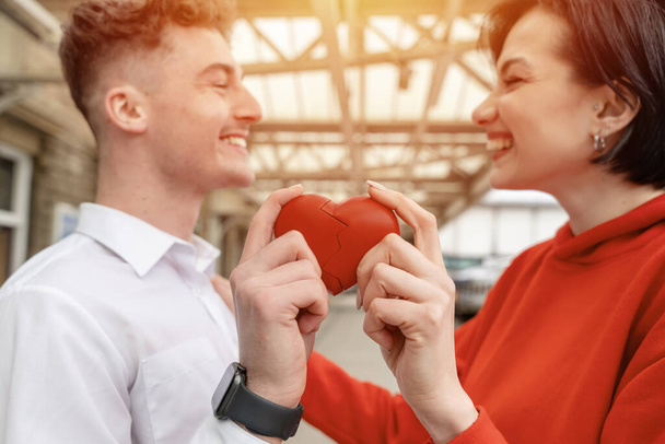 Happy Couple trying to connect two pieces of heart - relationship, in love concept - Photo, Image