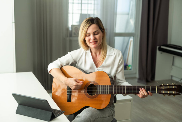 Νεαρή γυναίκα παίζει κιθάρα στο σπίτι. Υψηλής ποιότητας φωτογραφία - Φωτογραφία, εικόνα