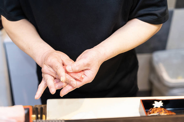 Sushin valmistusprosessi. Kokki valmistelee japanilaista perinteistä ruoanlaittoa. Prosessi tehdä ja koristelu lohi sushi. - Valokuva, kuva