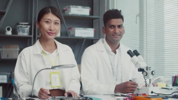 Közepes portré két vidám szerelő fehér kabátban mosolyog a kamera a szervizközpontban - Felvétel, videó