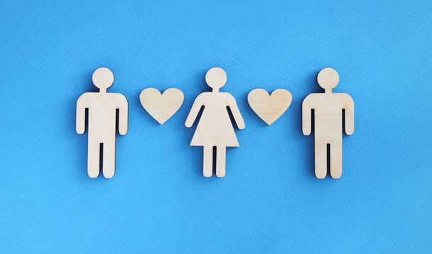Wooden figurines of men and women with hearts on blue background. Love triangle in relationship concept - Photo, Image