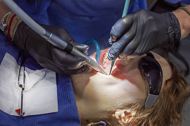 dívka na gauči zubaře nosí sluneční brýle během zubní léčby - Fotografie, Obrázek