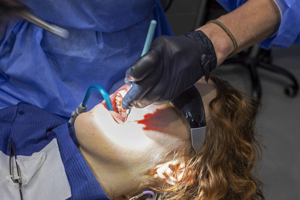 девушка на диване дантиста в солнечных очках во время стоматологического лечения - Фото, изображение