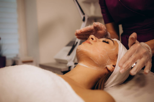un cosmetólogo realiza un procedimiento facial sedoso en una mujer. Foto de alta calidad - Foto, imagen
