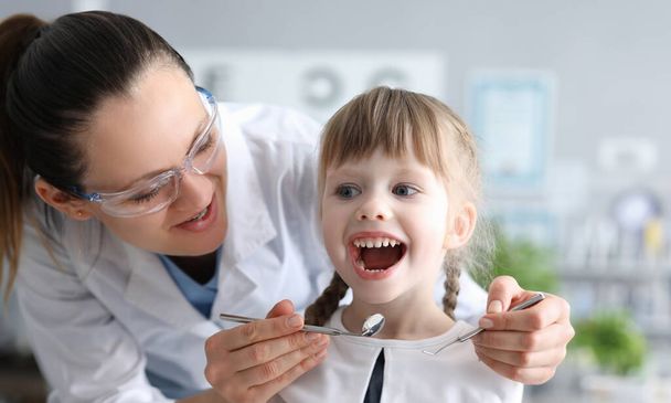 Dentysta badający usta małej dziewczynki z instrumentami. Badanie profilaktyczne koncepcji jamy ustnej - Zdjęcie, obraz