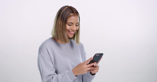 Funny chat, phone and woman laughing in studio with comic, joke or silly gif communication on white background. Smartphone, text and female model reading goofy social media, email or streaming video. - Footage, Video