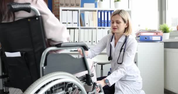 Vrouwelijke arts gebruikt hamer slag op knie van de patiënt in een rolstoel. Verwonding spierherstel en knievervanging artrose - Video