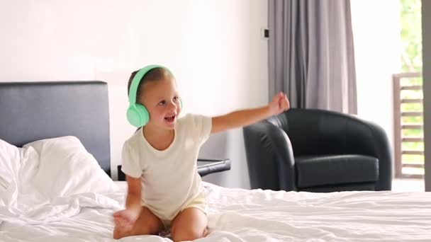 Menina engraçada ouvindo a música com fones de ouvido crianças e dançando em casa na manhã feliz. Imagens 4k de alta qualidade - Filmagem, Vídeo