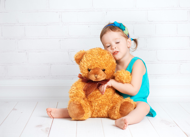 meisje van de baby een geliefde teddy bear knuffelen - Foto, afbeelding