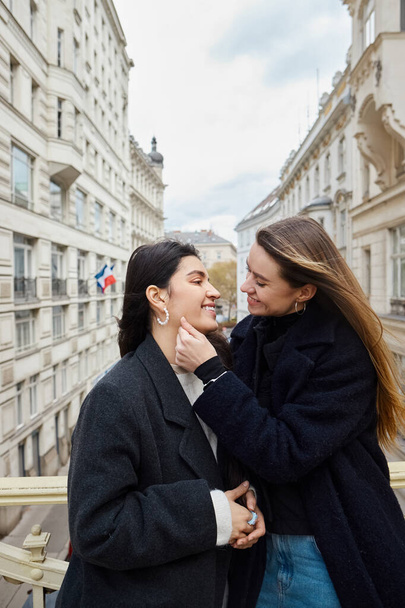 Şehir mimarisinin arka planı ile balkonda samimi bir an, birbirine aşık iki lezbiyen kadın. - Fotoğraf, Görsel