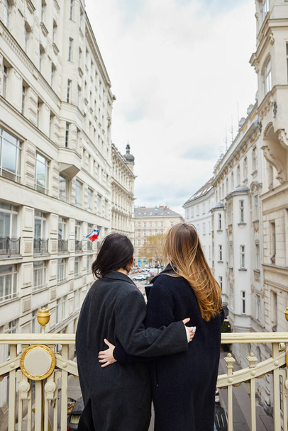 Інтимний момент на балконі з видом на місто як фон, вид ззаду лесбійок закоханих - Фото, зображення
