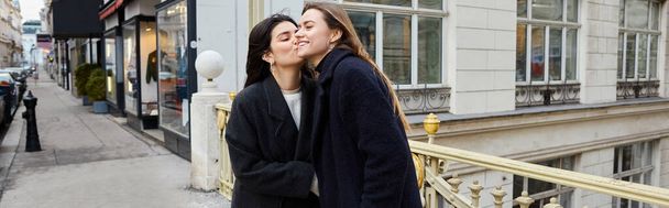 Kameralny moment zakochanych lesbijek stojących razem na ulicy w europejskim mieście, sztandar - Zdjęcie, obraz