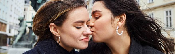 счастливая лесбиянка целует в щеку свою девушку у фонтана статуи в Вене, баннер - Фото, изображение
