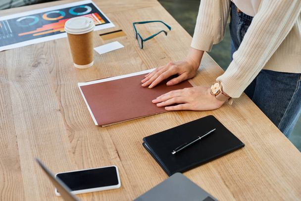 Een zakenvrouw in een modern kantoor richt zich op haar werk, aan haar houten tafel omringd door een franchiseconcept. - Foto, afbeelding