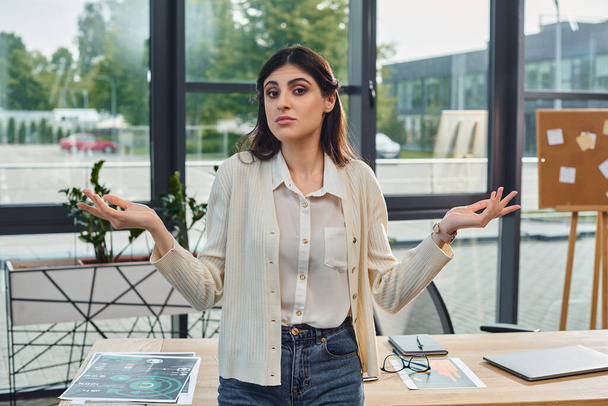 Eine moderne Geschäftsfrau steht selbstbewusst vor ihrem Schreibtisch in einem eleganten Büroambiente. - Foto, Bild
