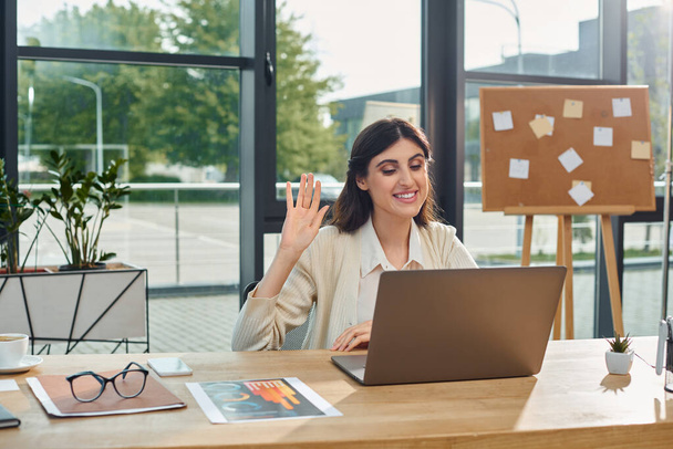 Une femme d'affaires dans un bureau moderne est assise devant un ordinateur portable, profondément dans la pensée alors qu'elle travaille sur un concept de franchise. - Photo, image