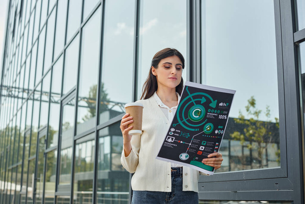 Bizneswoman w nowoczesnym otoczeniu biurowym na świeżym powietrzu, trzymając filiżankę kawy i wykresy, symbolizujące równowagę pracy i relaksu. - Zdjęcie, obraz