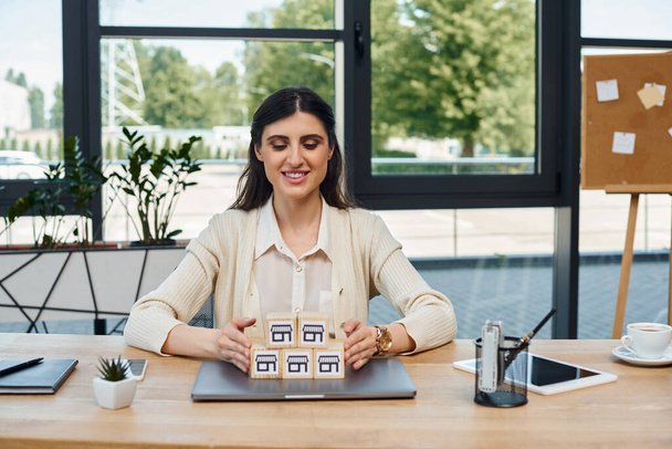Bizneswoman siedzi przy stole, koncentrując się na blokach w nowoczesnym biurze, ucieleśniając koncepcję franczyzy. - Zdjęcie, obraz