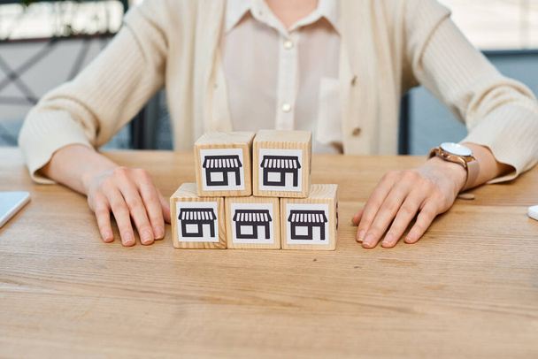 Una mujer de negocios se sienta en una mesa, contemplando un conjunto de bloques delante de ella, simbolizando el concepto de construir sueños de negocios. - Foto, imagen