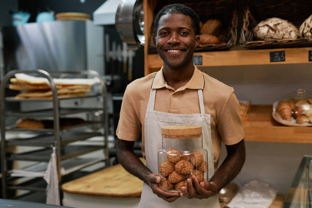 Muotokuva hymyilevä leipomon työntekijä tilalla lasipurkki kaurapuuro evästeet - Valokuva, kuva