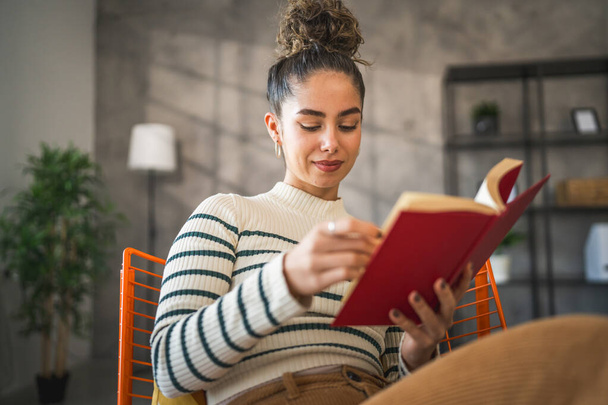 fiatal felnőtt nő egy nő olvasni könyvet vagy tanulmány otthon - Fotó, kép
